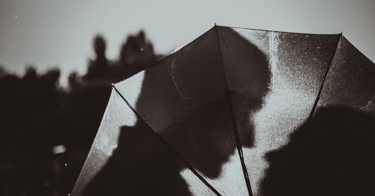 Sombras de um homem e de uma mulher vistas através de um guarda-chuva.