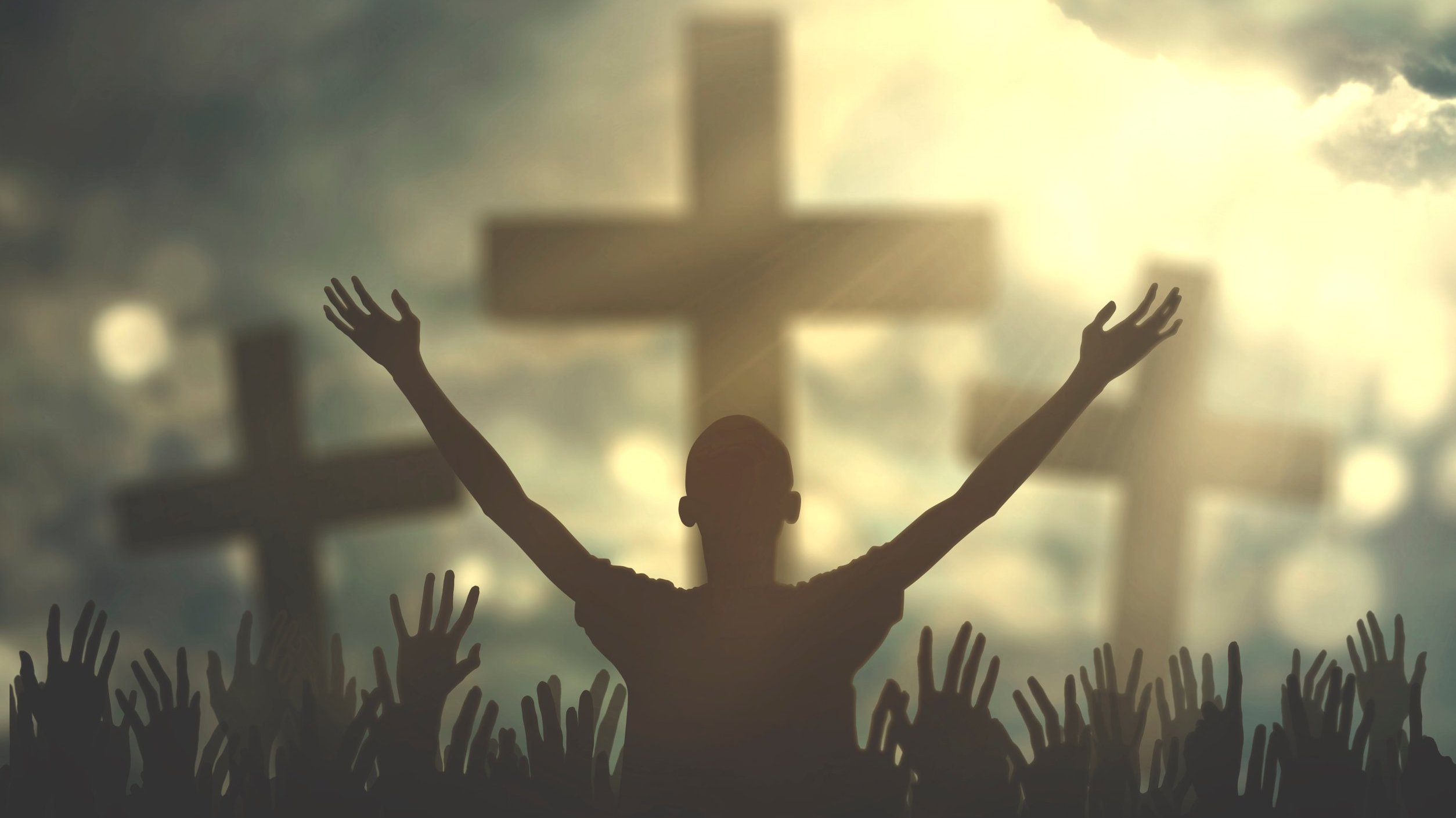 Pessoa com braços abertos em direção a uma cruz