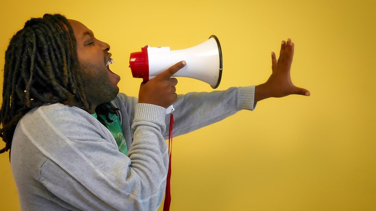 homem negro de trança segurando um megafone