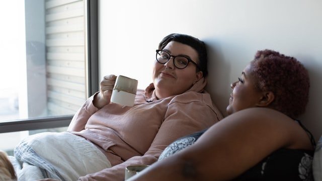 duas mulheres deitadas na cama se olhando e demonstrando intimidade