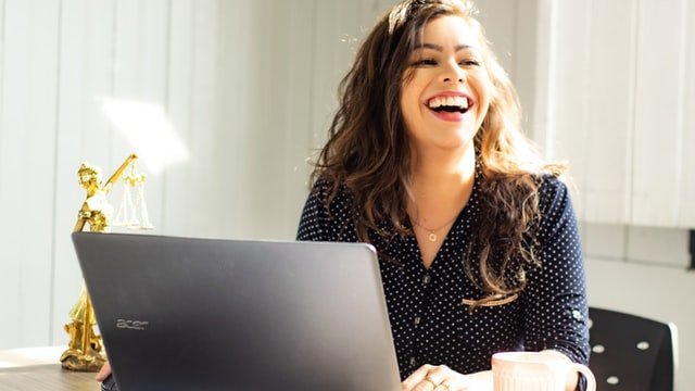 mulher rindo em frente a um nootbook