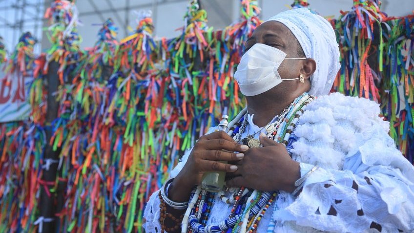 Homem vestido com roupas da umbanda com as mãos no peito