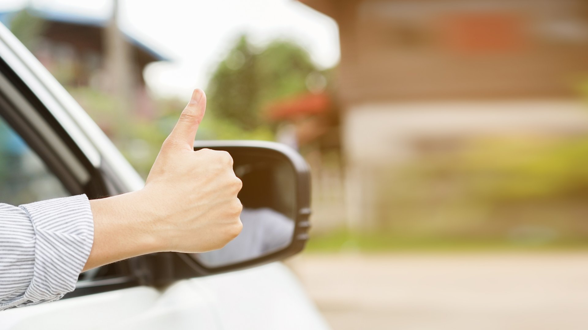 Uma pessoa realizando um gesto de joia, exibindo-o para fora da janela de um carro.