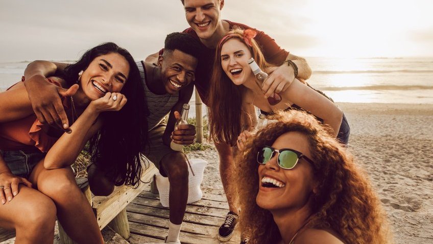 Grupo de três mulheres e dois homens se divertindo na praia