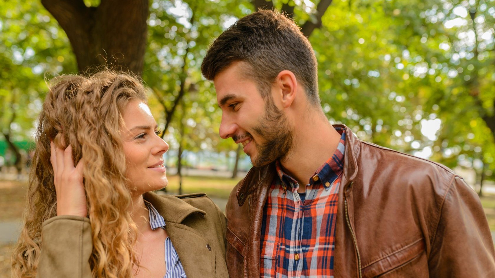 Uma mulher, à esquerda, e um homem, à direita. Ambos se olham e sorriem um para o outro.