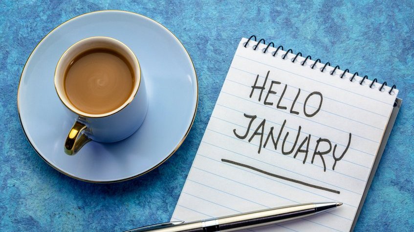 Uma xícara com café em cima de um prato e uma caderneta escrito ''olá janeiro'' em inglês