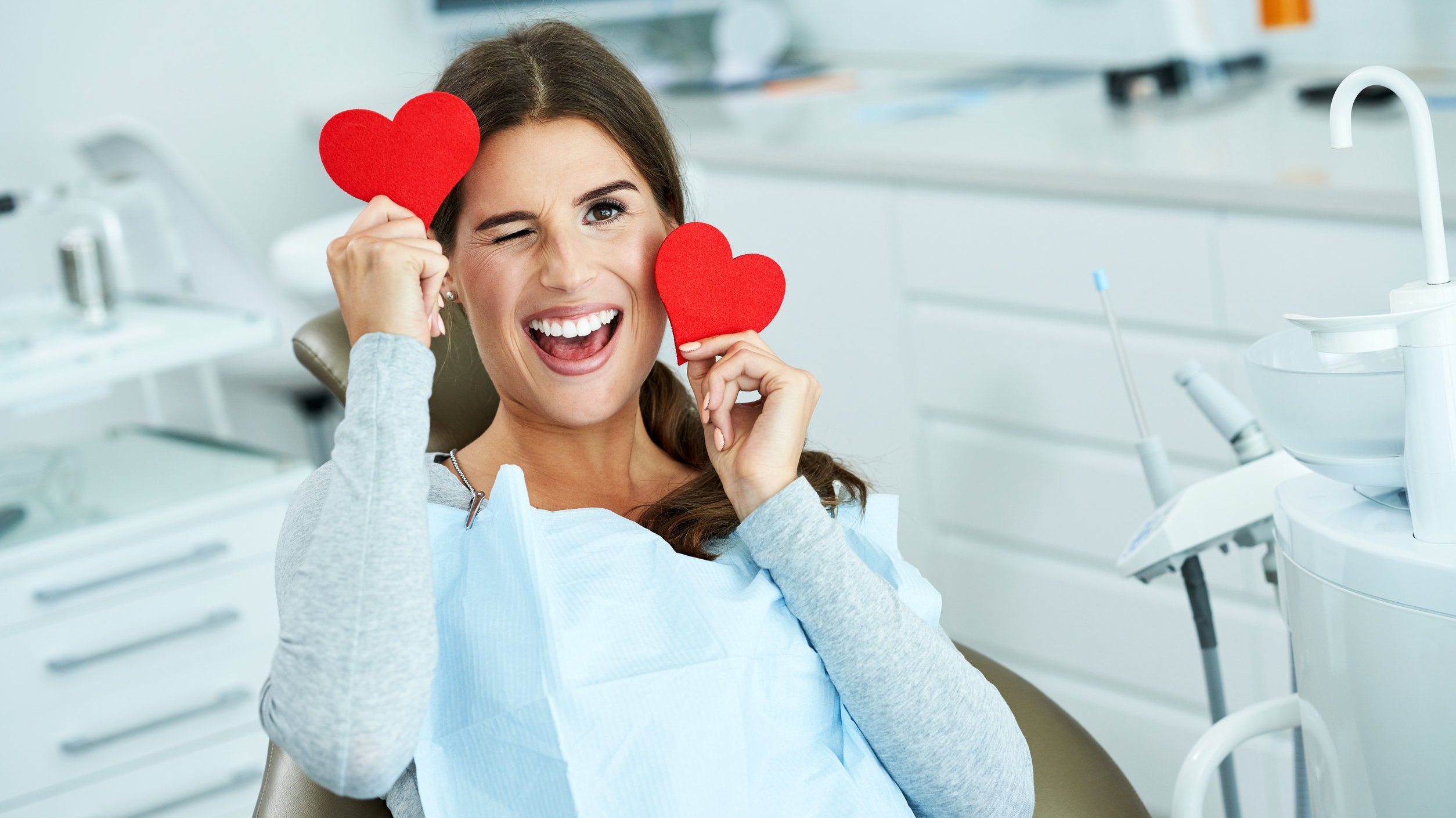 Mulher mostrando corações em um consultório de dentista