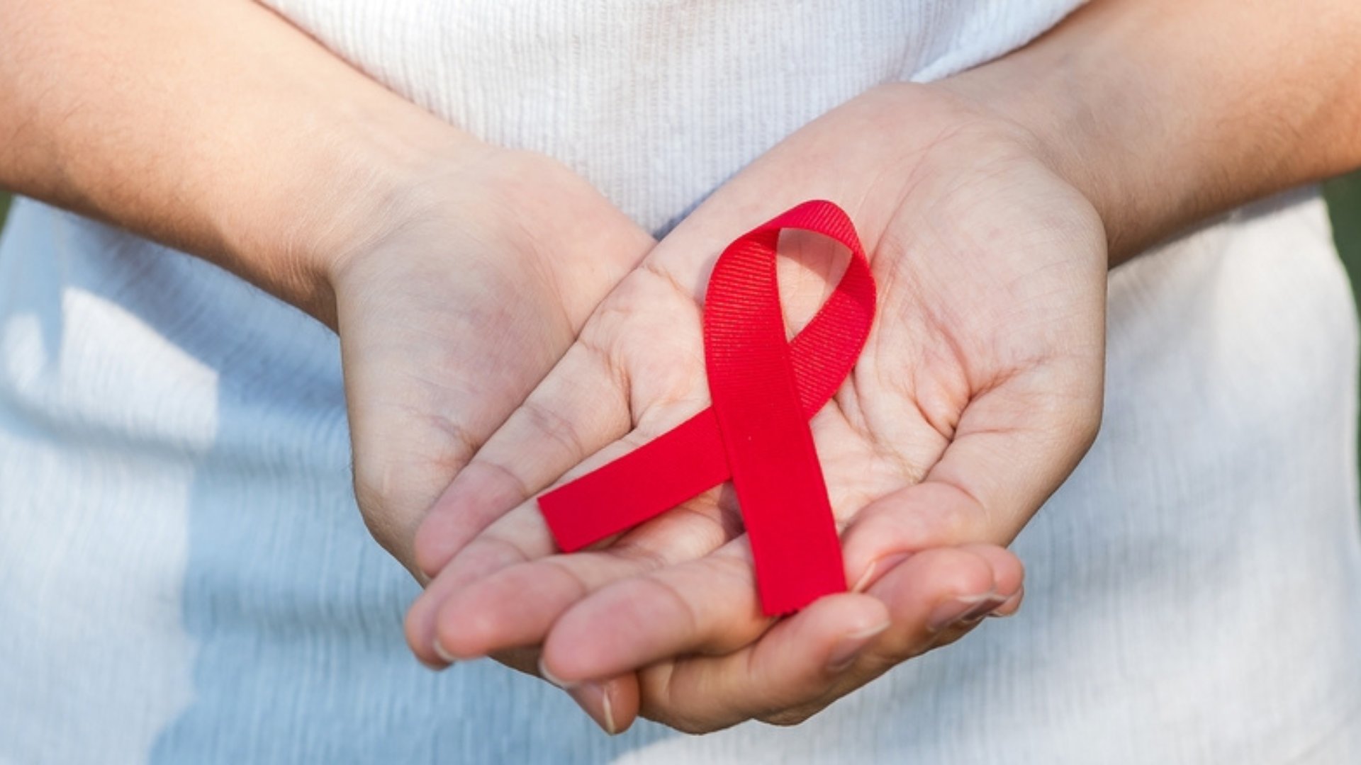 Uma pessoa segurando um laço vermelho. Este representa, durante o mês de março, o símbolo do combate e da conscientização ao câncer renal.