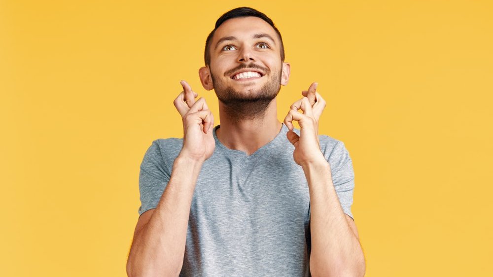 homem sorrindo e torcendo os dedos em sinal positivo