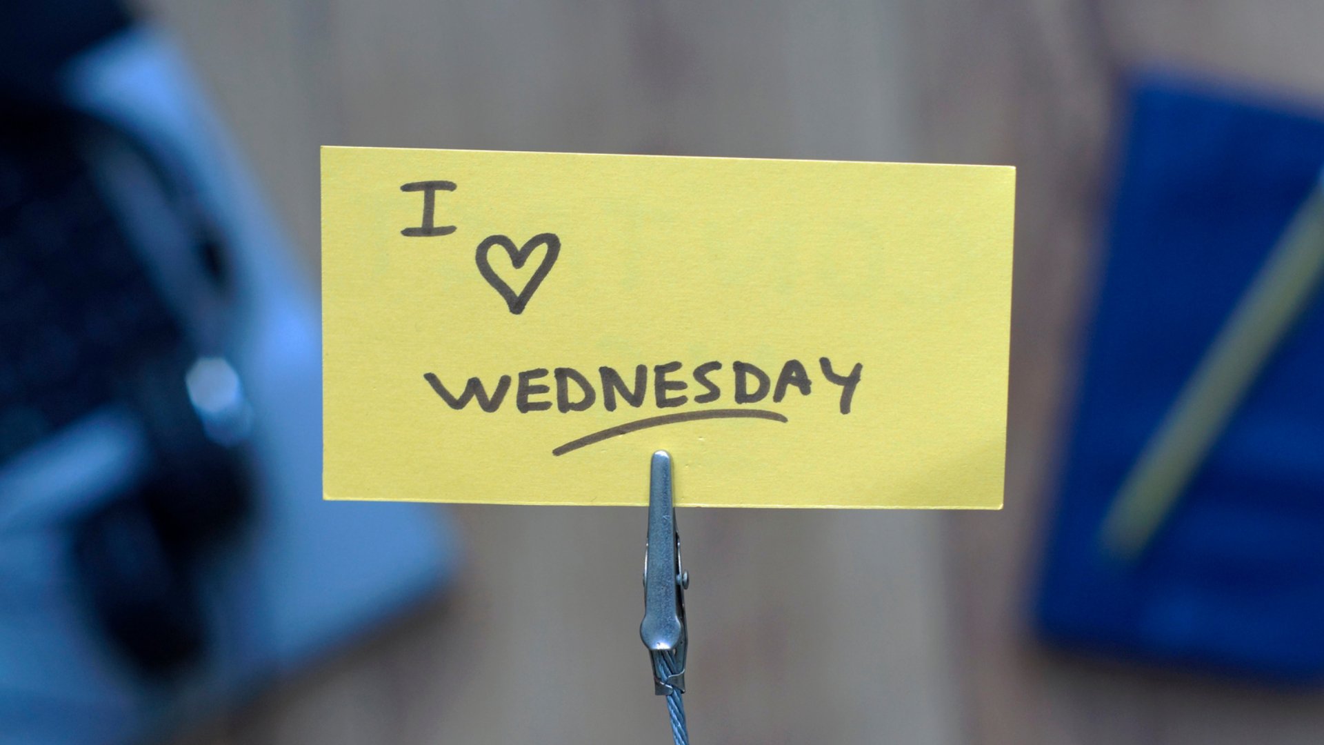 Um pequeno papel amarelo que tem escrita a frase: 'i (um desenho de coração) wednesday'. Traduzida, significa: 'eu amo quarta-feira