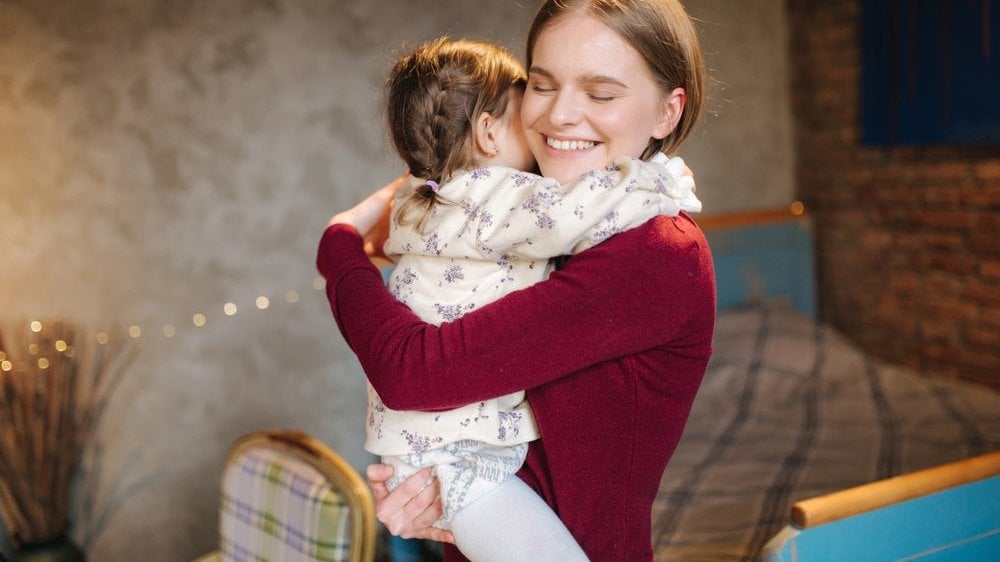Uma mulher branca e sorridente segurando um bebê.