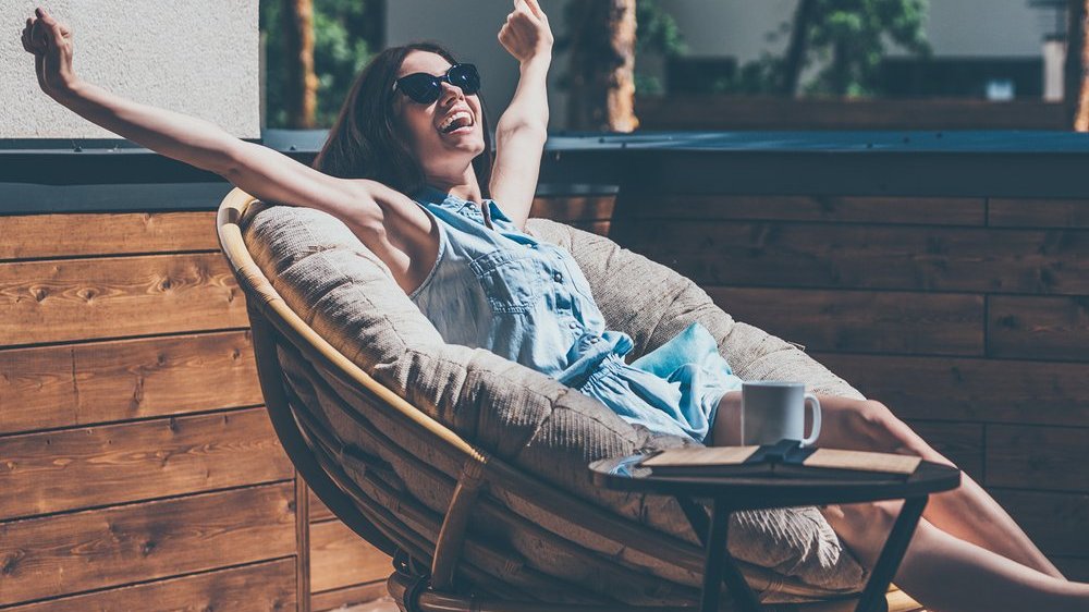 mulher sorridente de braços abertos ao céu