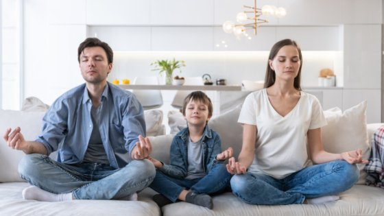 Homem, mulher e filho criança meditando no sofá
