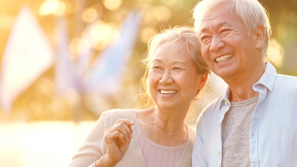 Um homem e uma mulher idosos e asiáticos sorrindo.