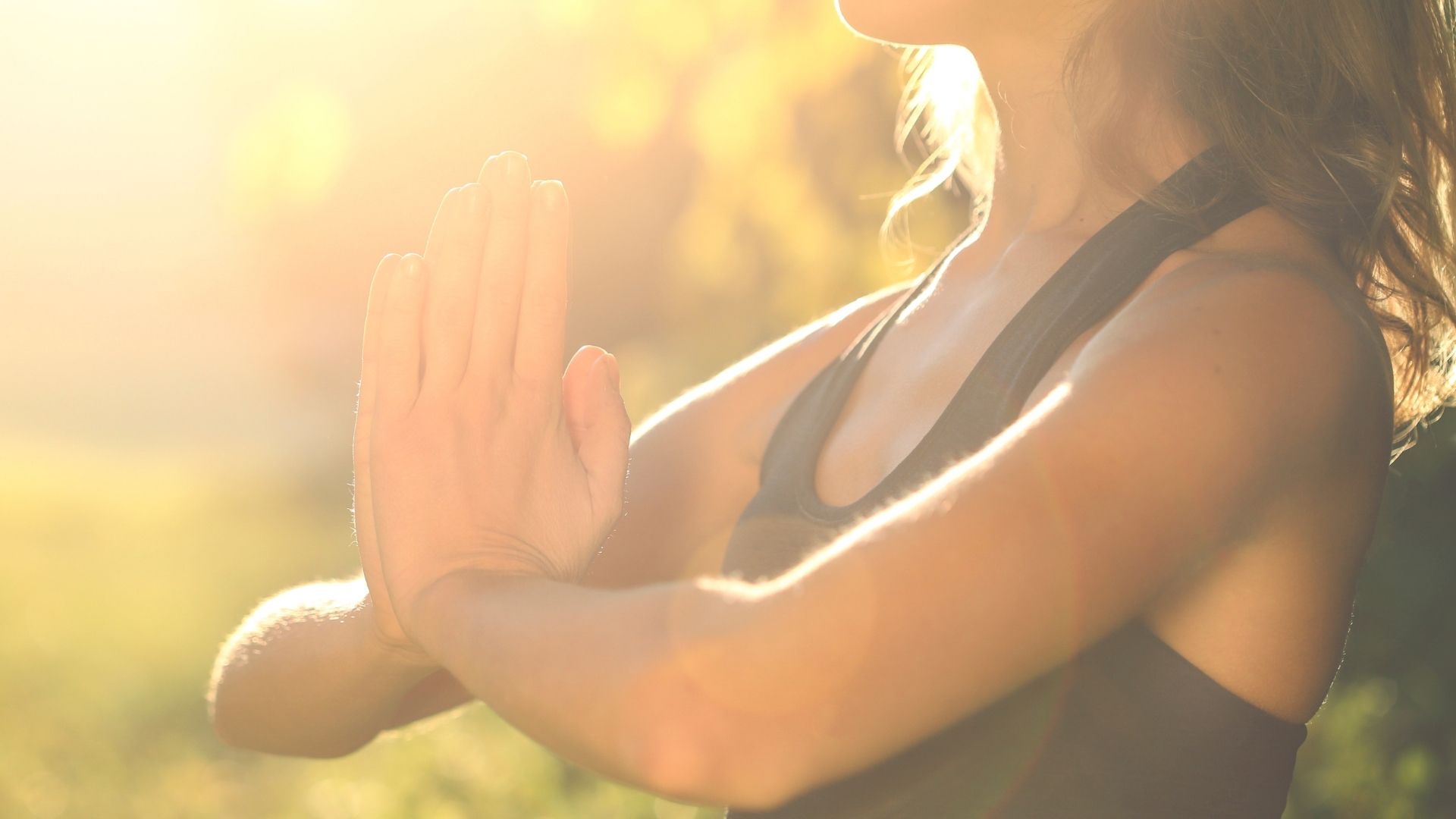 Uma mulher cruzando suas mãos e realizando um gesto típico de oração/meditação.