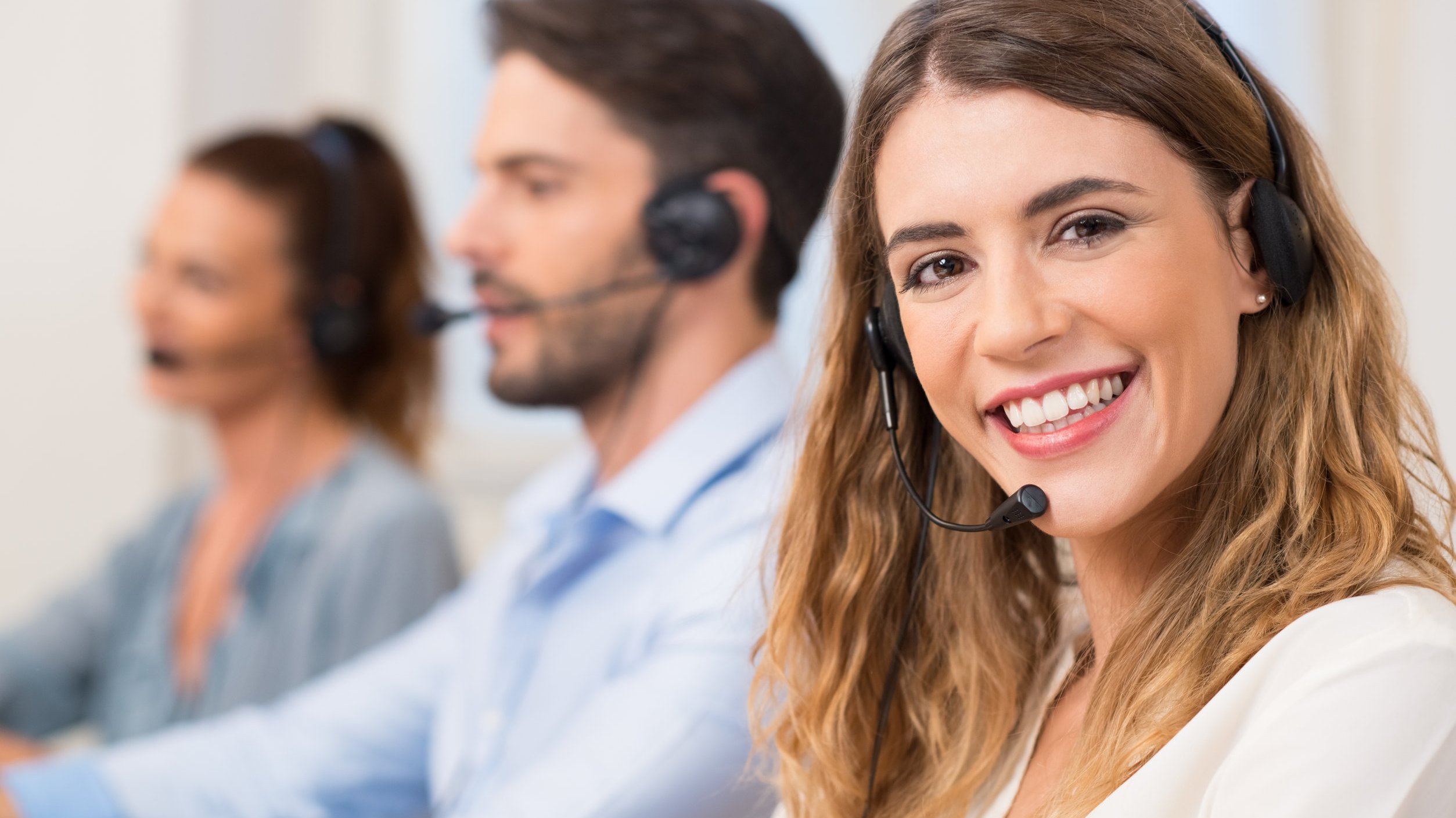 Mulher de telemarketing com fone sorrindo para foto