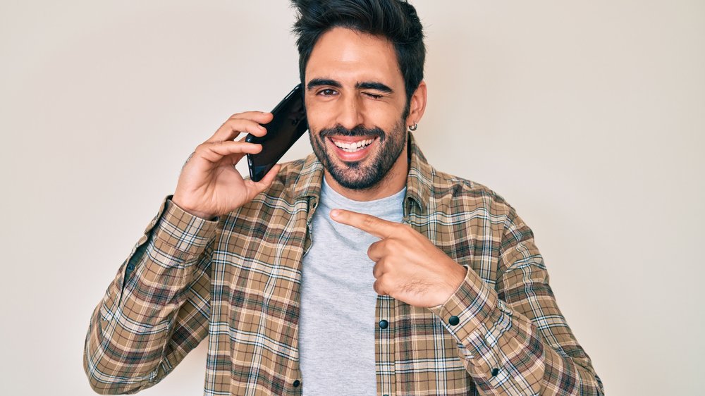 Homem sorrindo e usando o celular