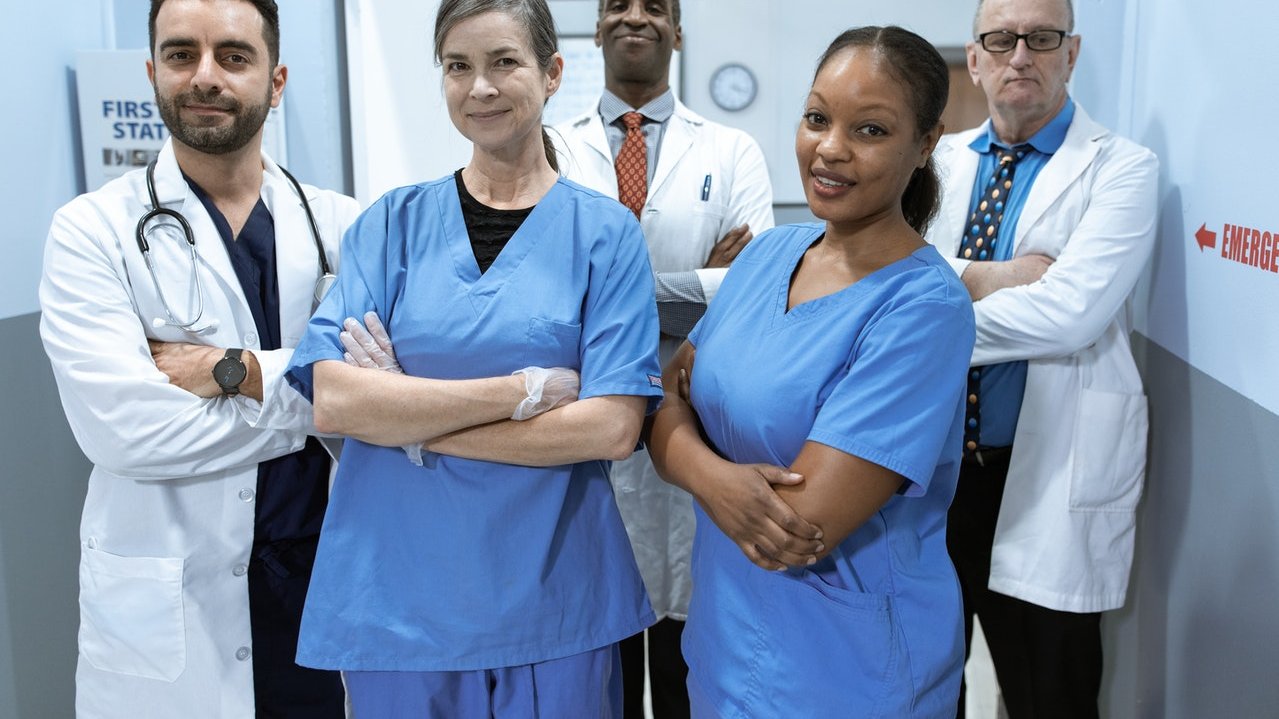 Médicos juntos de braços cruzados sorrindo para foto