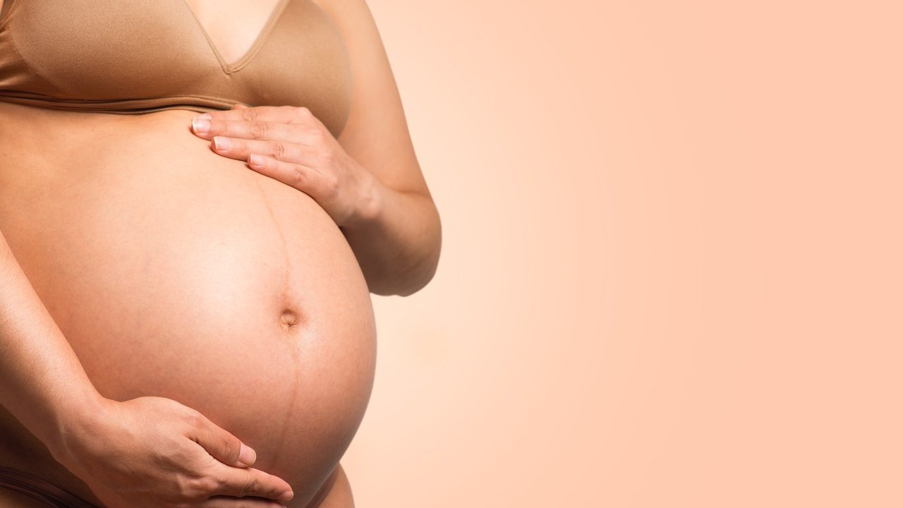 Mulher grávida com as mãos na barriga