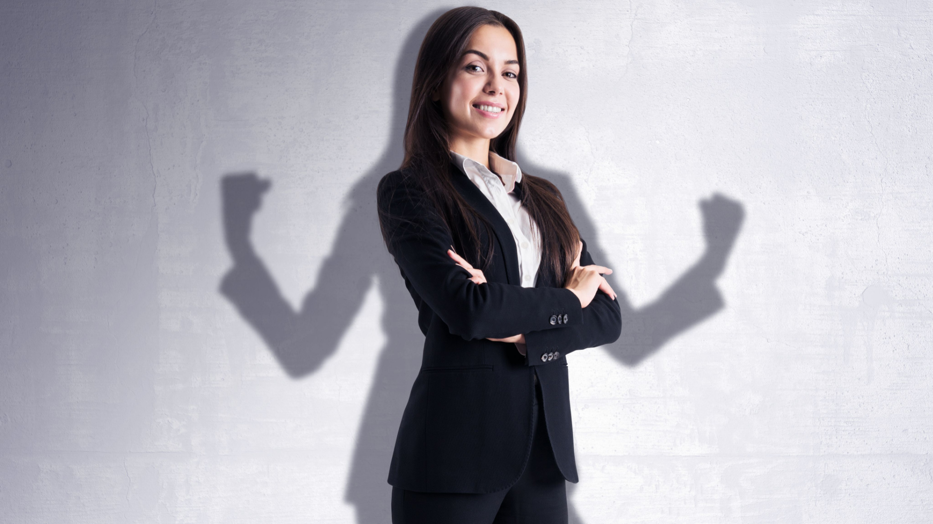 Golden Dayz / Shutterstock Liderança e empoderamento de uma empresária em uma sombra atrás dela na parede