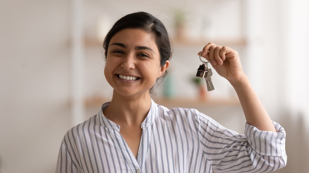 Uma mulher segurando chaves de uma casa.