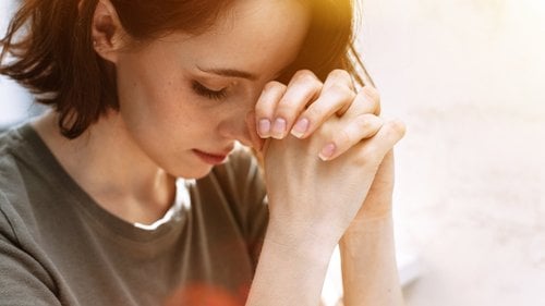 Mulher com as mãos juntas rezando