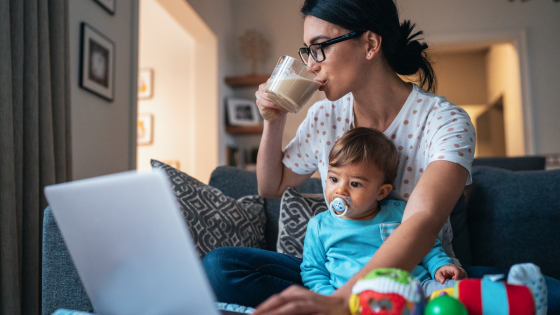 Mãe trabalhando enquanto toma um café e olha seu filho