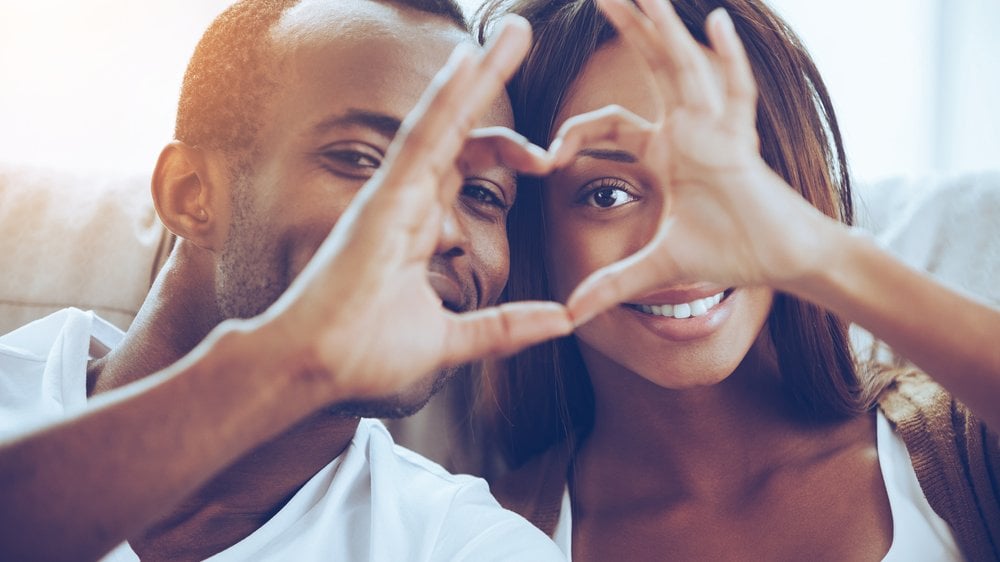 Casal hétero fazendo coração com as mãos