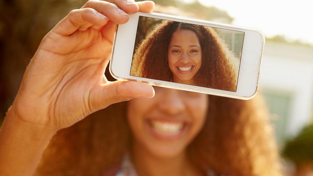 Mulher tirando selfie sozinha sorrindo