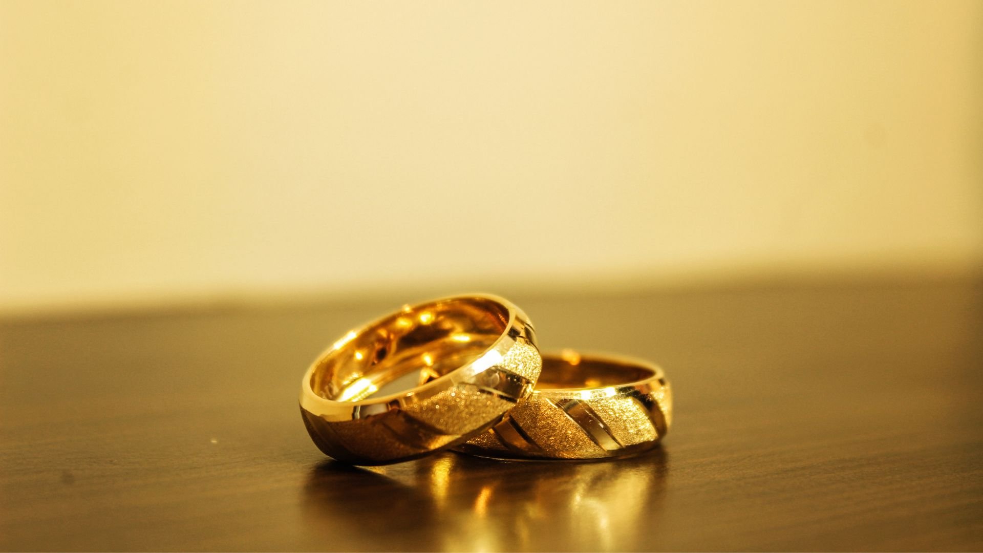 Imagem de duas alianças douradas em uma mesa de madeira
