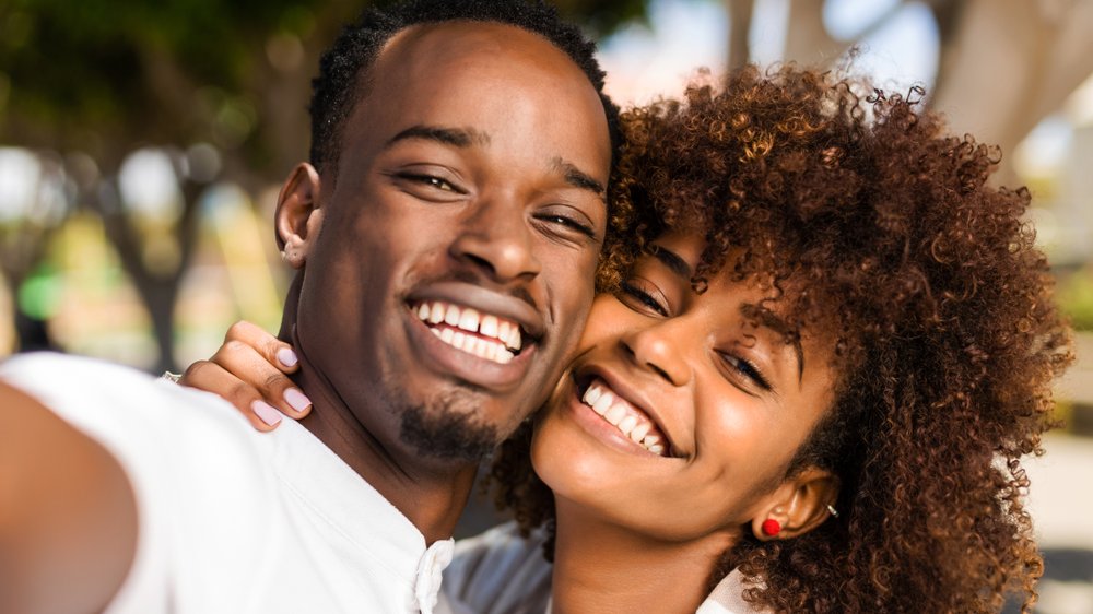 Casal hétero negro tirando uma selfie sorrindo