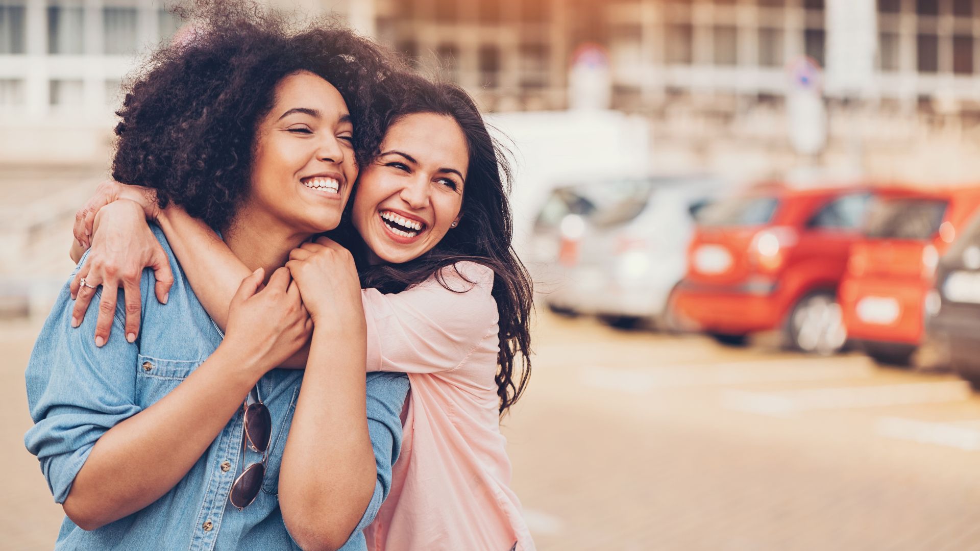 Imagem de um casal de lésbicas abraçadas e sorrindo