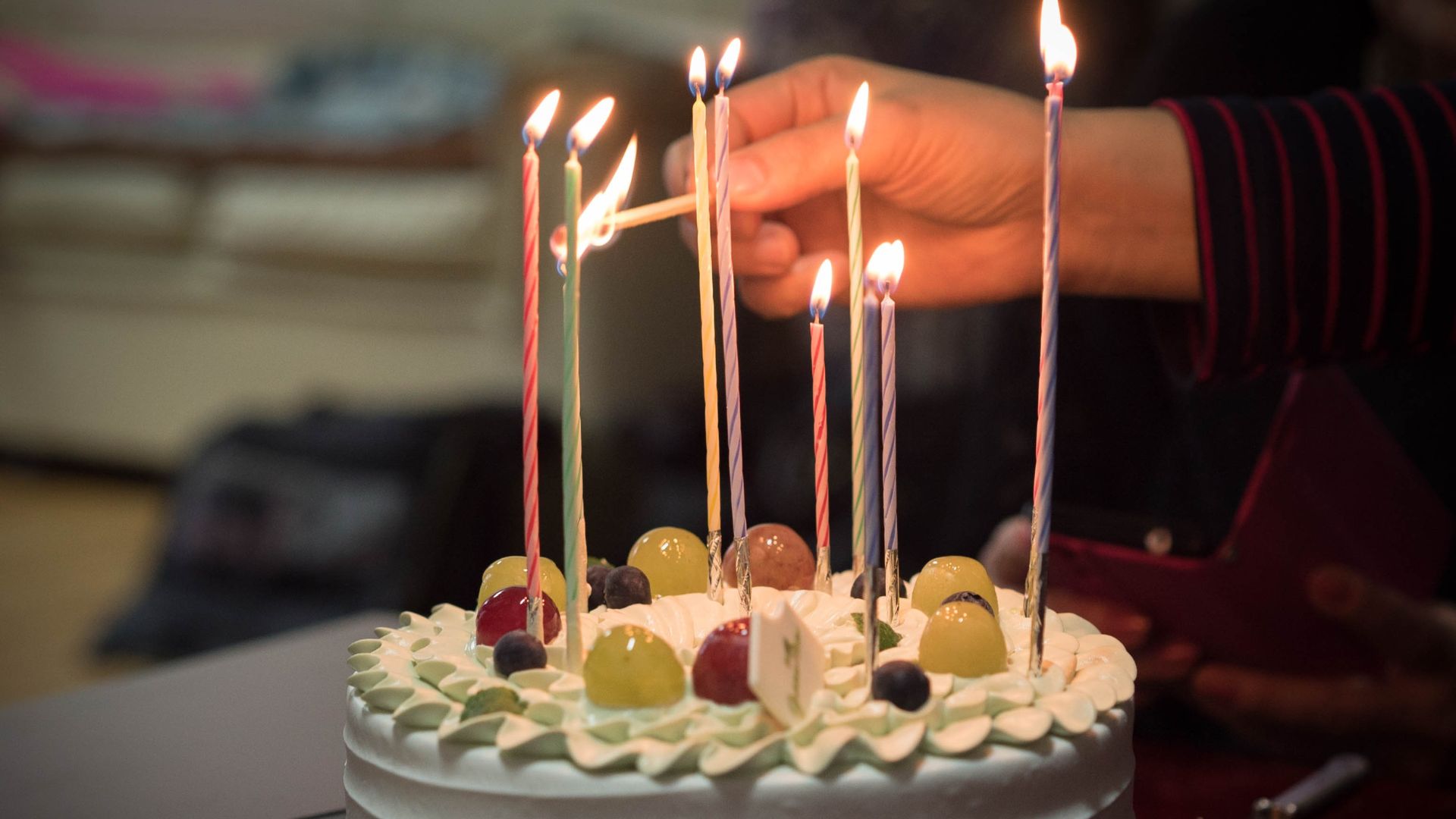 Imagem de uma pessoa aendendo as velas que estão no topo do bolo