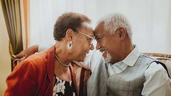 Casal de isosos com as testas encostadas, sorrindo.