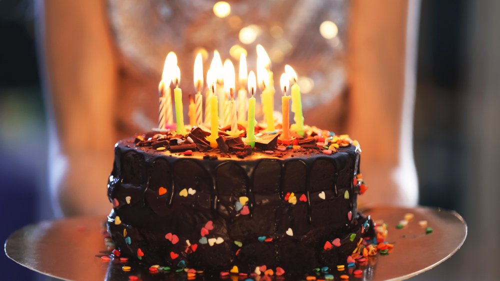 Bolo de aniversário confeitado e cheio de velas coloridas