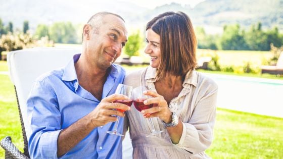 Homem e mulher com taça de vinho na mão, brindando
