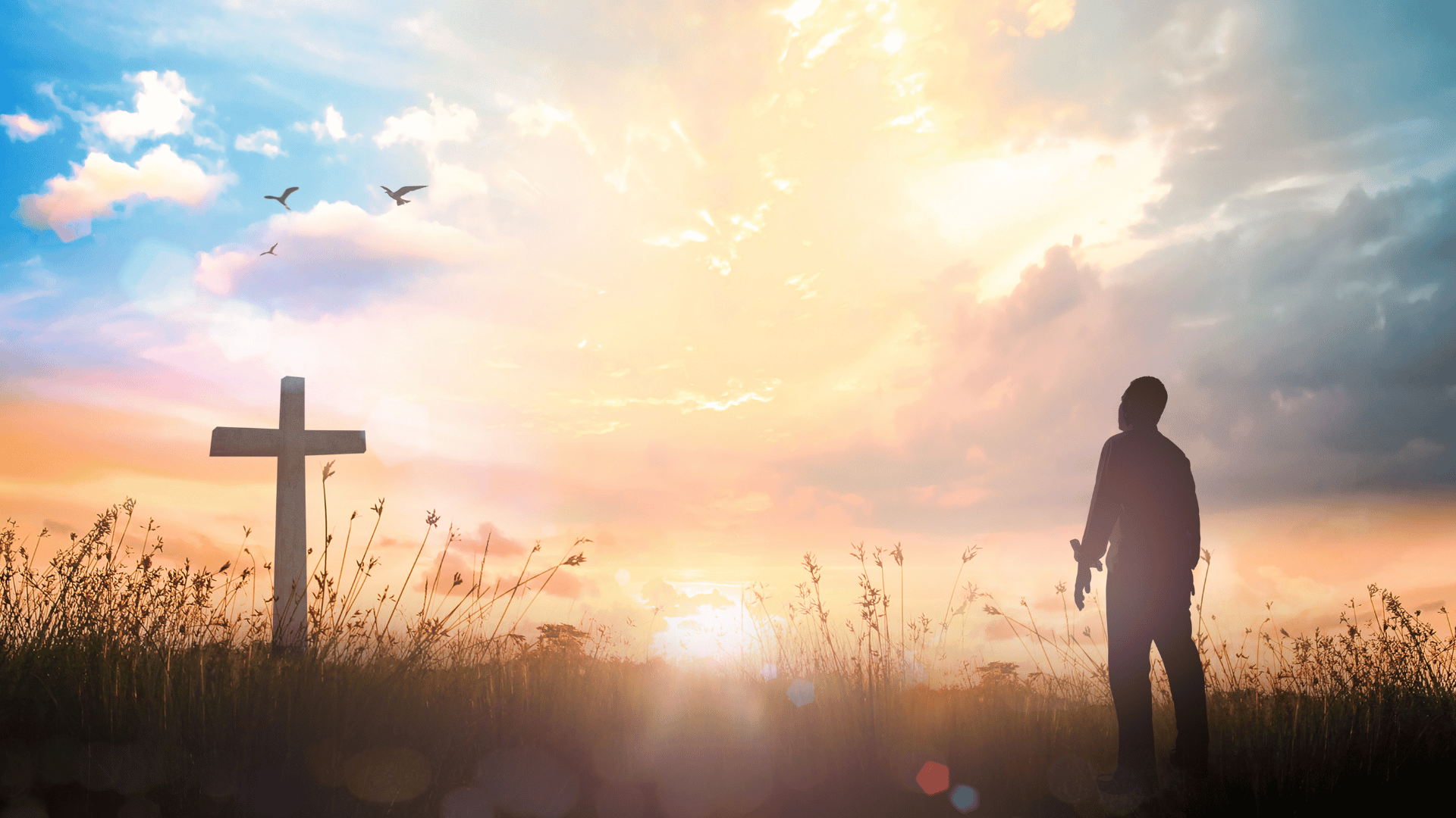Homem olhando esperançoso para uma cruz em um campo ao pôr do sol.