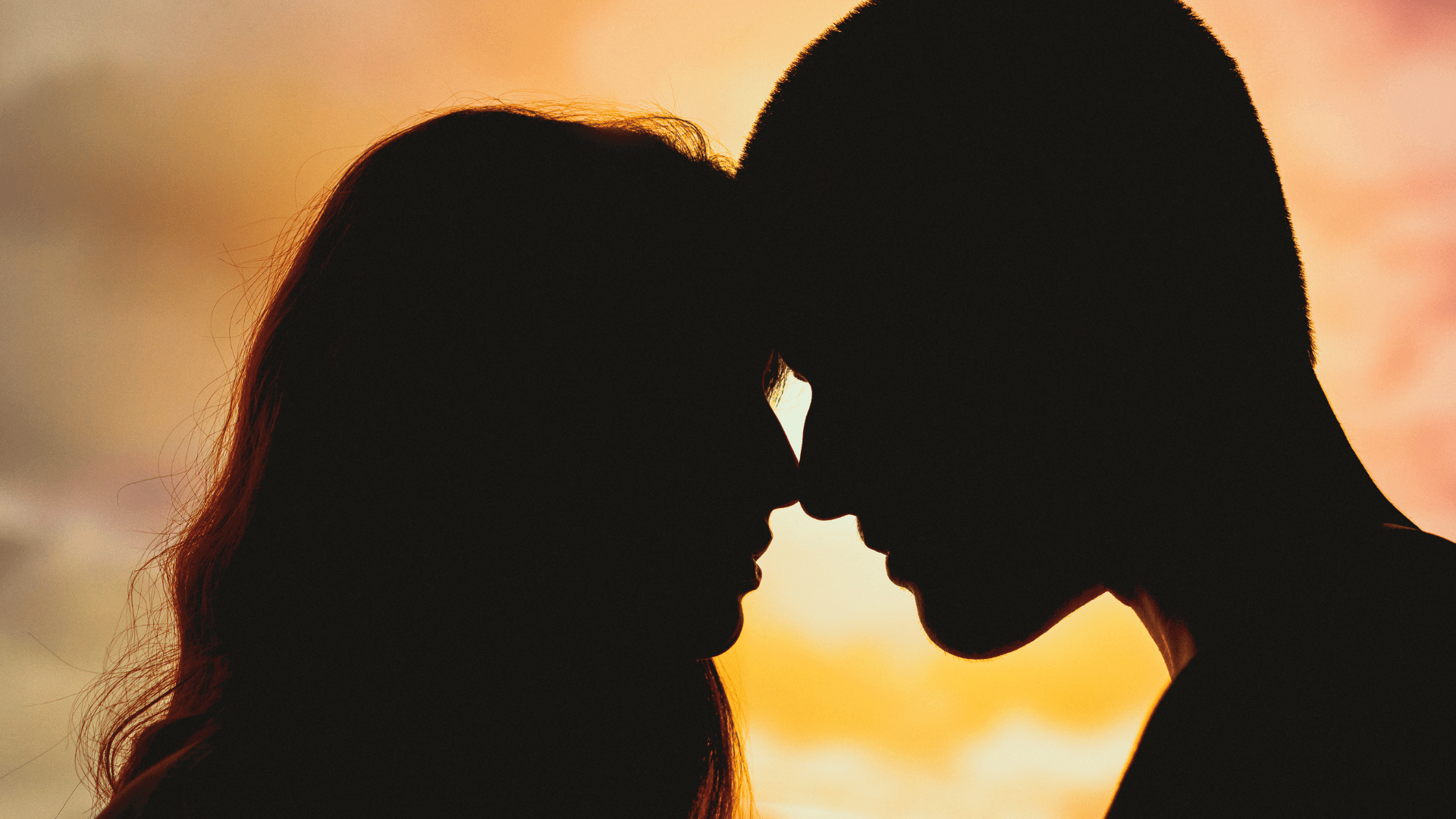 Casal com os rostos encostados com um fundo de pôr do sol