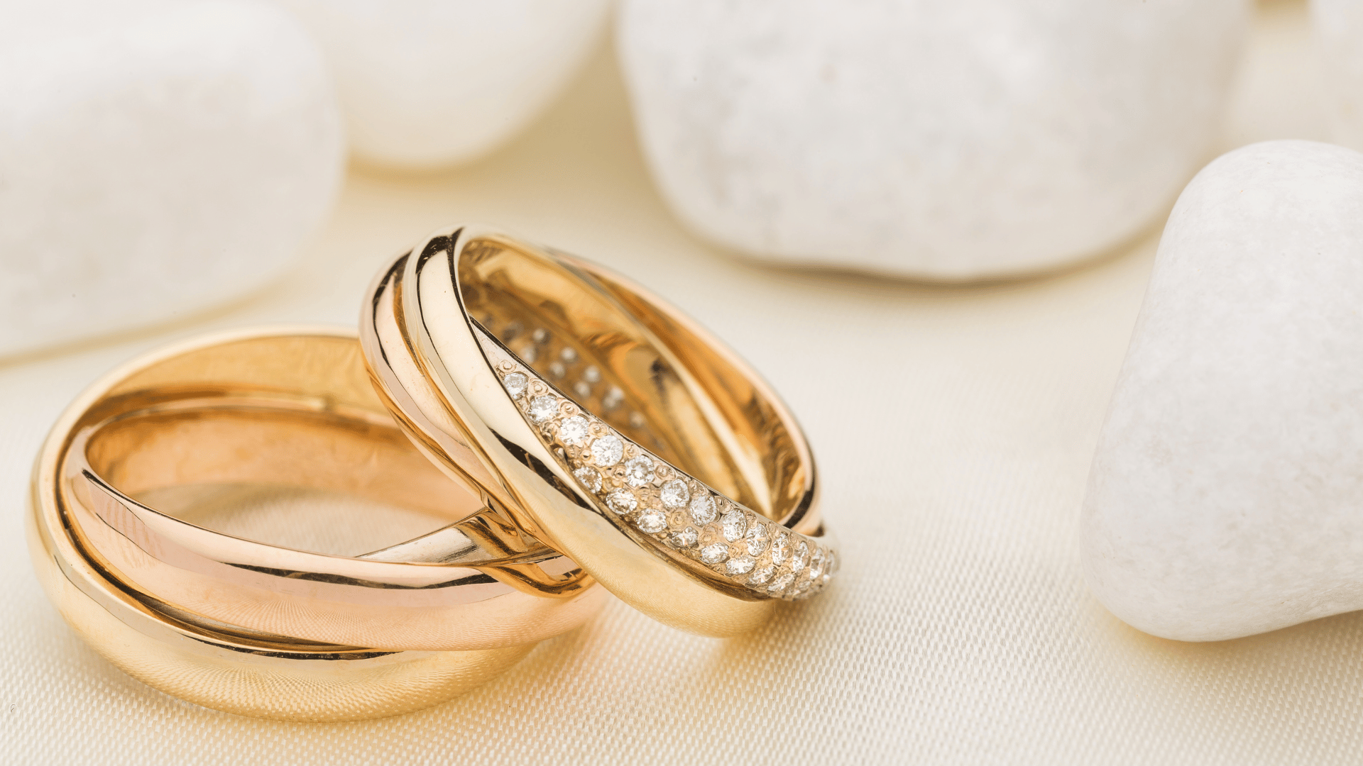 Duas alianças de casamento juntas em um fundo com pedras brancas.