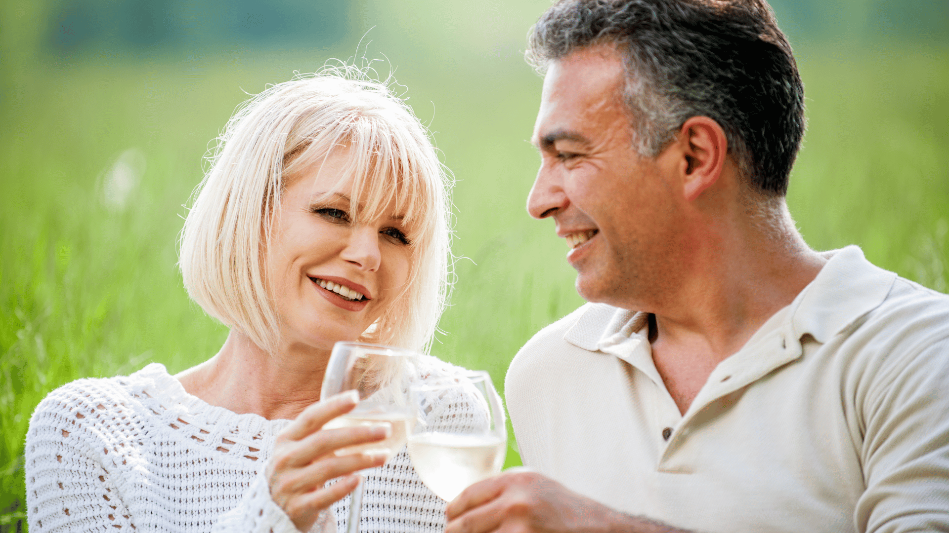 Casal de adultos tomando champagne em um jardim.