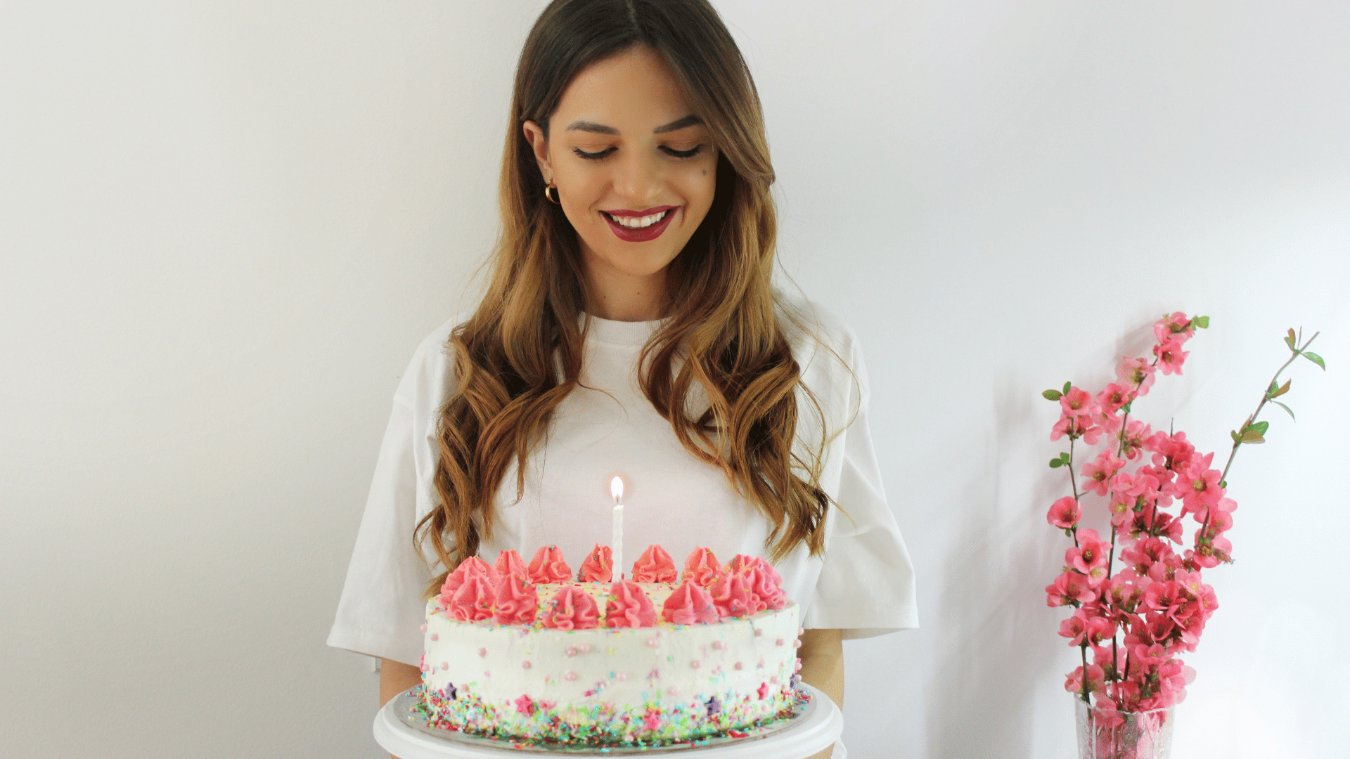Garota loira comemorando seu aniversário com um bolo na mão.