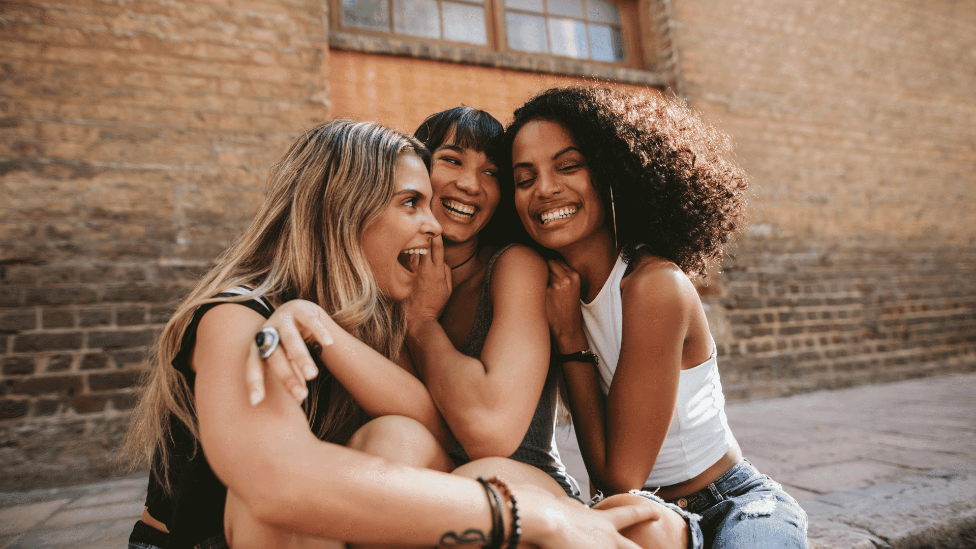 Trio de amigas abraçadas sorrindo.