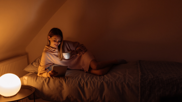 Mulher feliz na cama lendo no Kindle