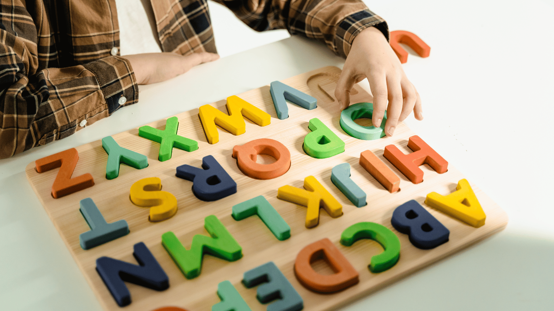 Criança brincando com quebra-cabeça de alfabeto.