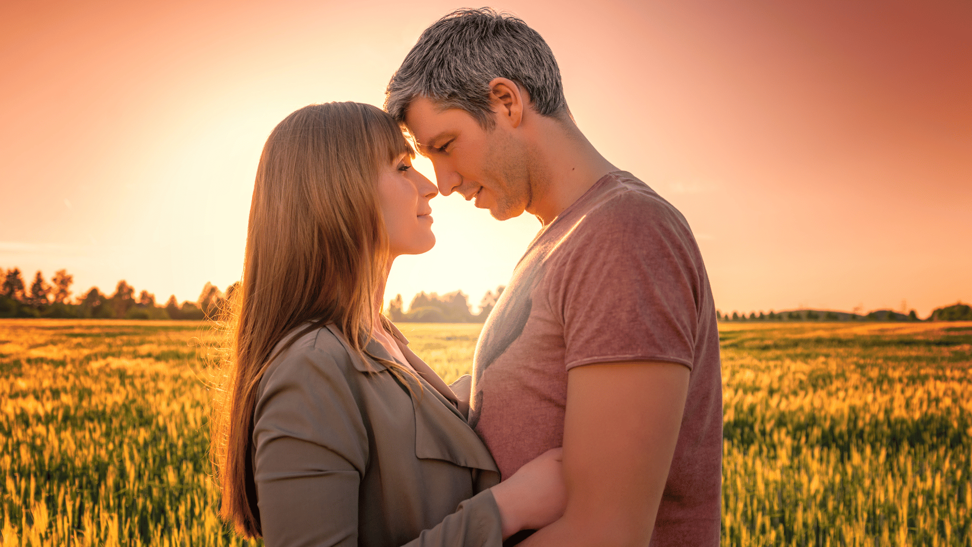 Casal com as faces próximas em fundo de pôr do Sol.