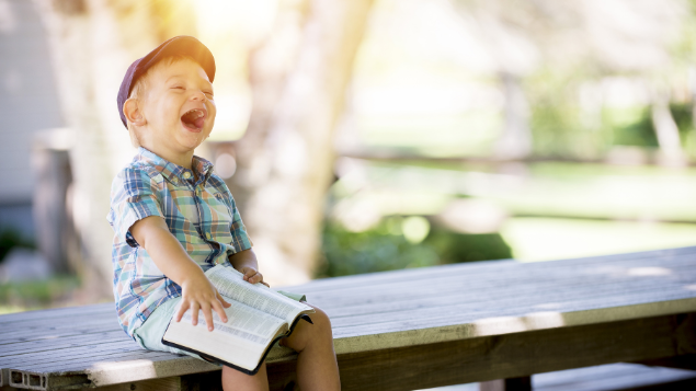 Criança rindo sentada em banco de praça