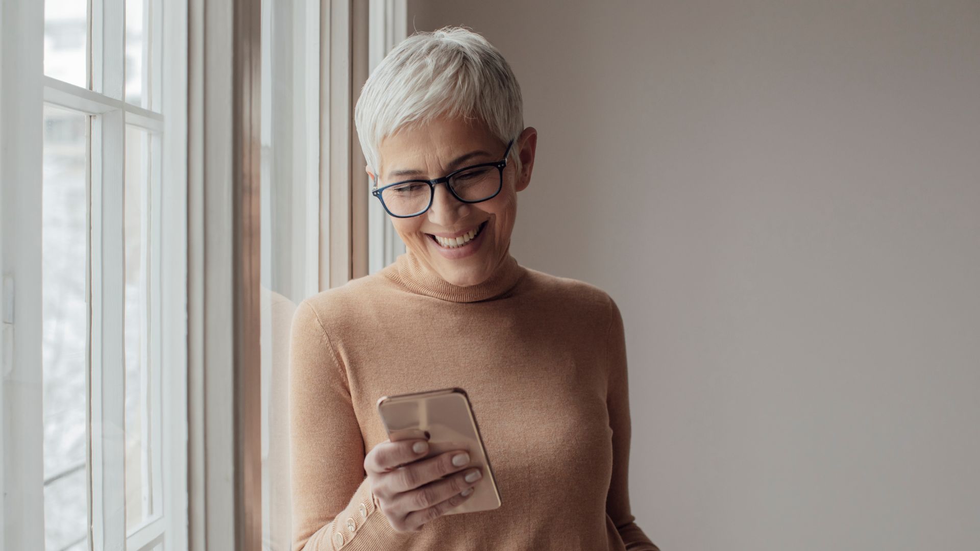 Mulher de meia idade olhando para o celular e sorrindo