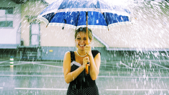 Mulher sorrindo enquanto está na chuva